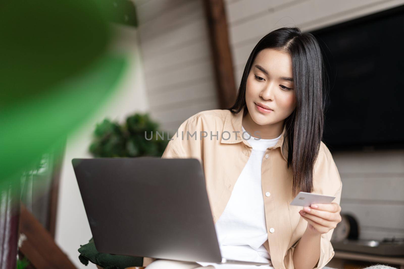 Portrait of asian girl buying on website with laptop and credit card. Young woman purchase online, sitting at home and shopping in internet.