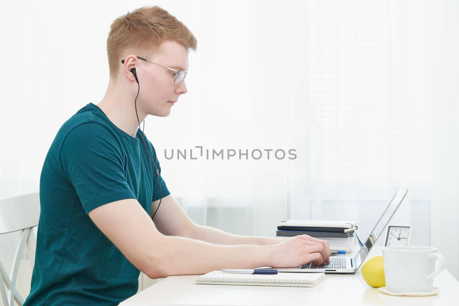 Distance education for students. Quarantine, self-isolation, sociophobia. Young teen listens to online learning, teleworking, online lectures. Man look at laptop. Freelancer, Digital Nomad Concept