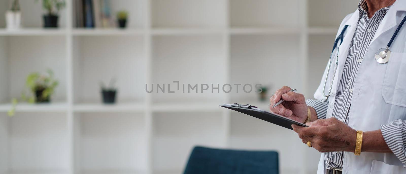 Cropped shot of doctor in uniform with stethoscope taking notes in medical history of patient on clipboard.