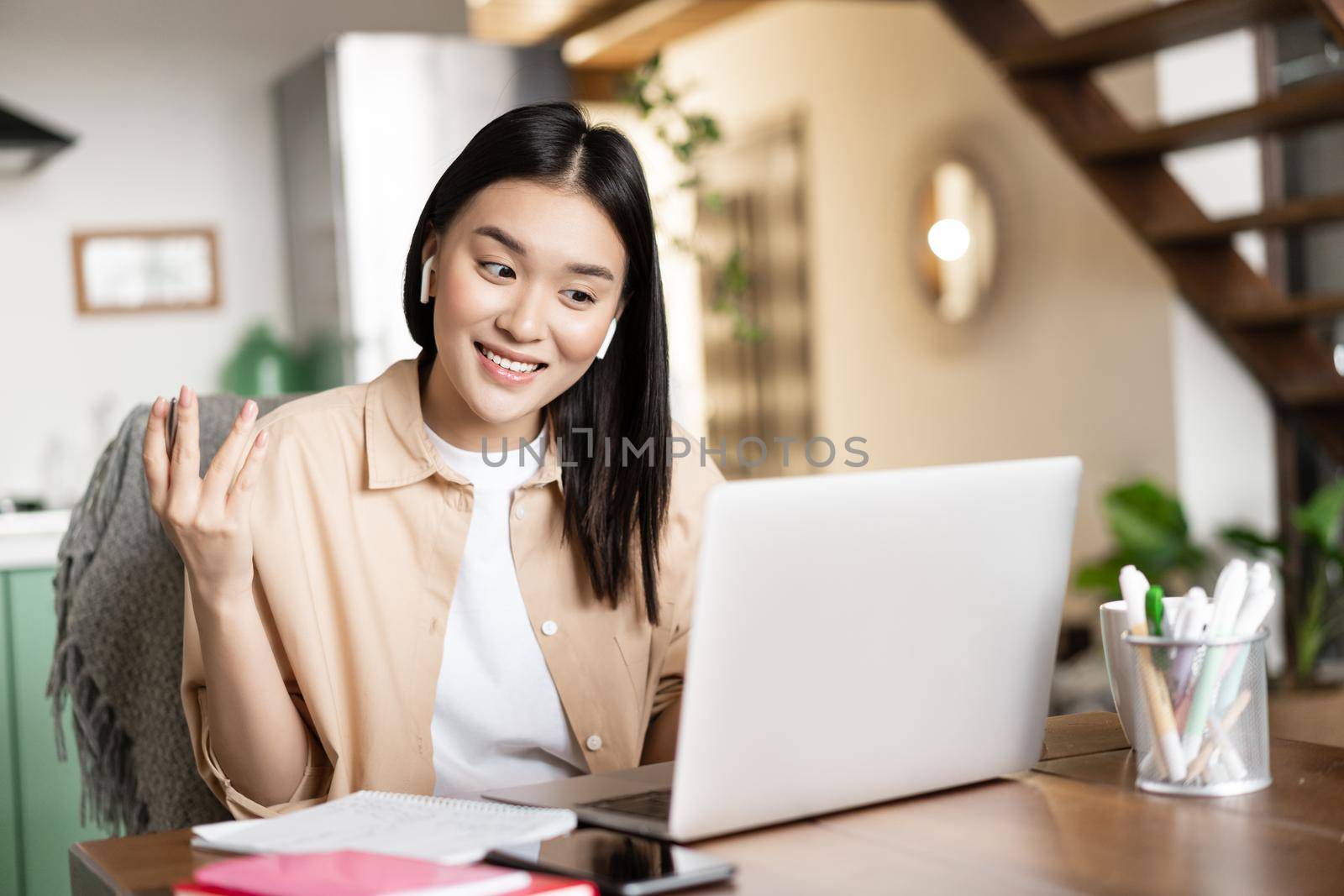 Smiling asian woman talks on video conference, working from home remotely with laptop, studying at online course or attending lecture.