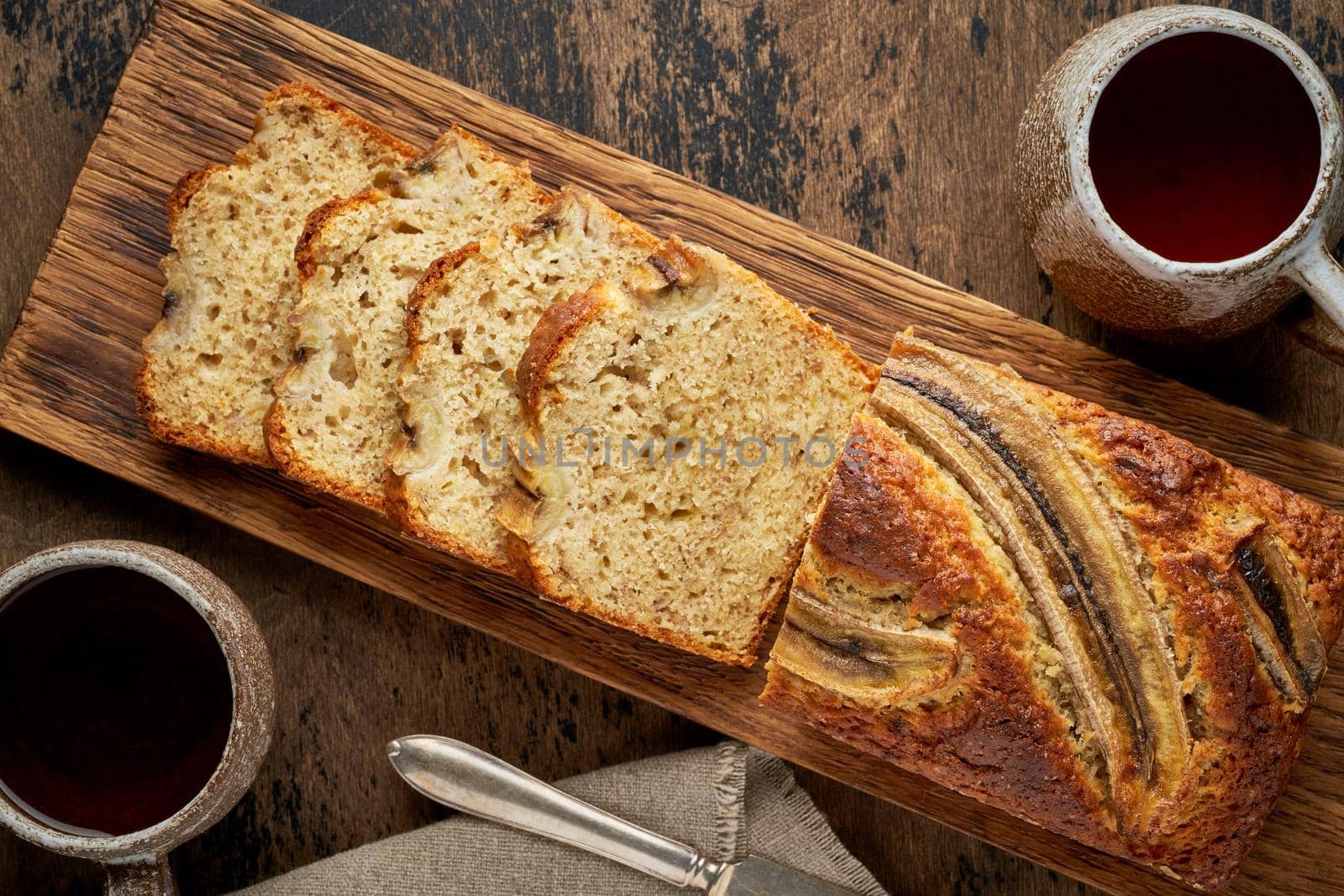 Banana bread. Cake with banana, traditional american cuisine. Slices of loaf. Dark background, black table.