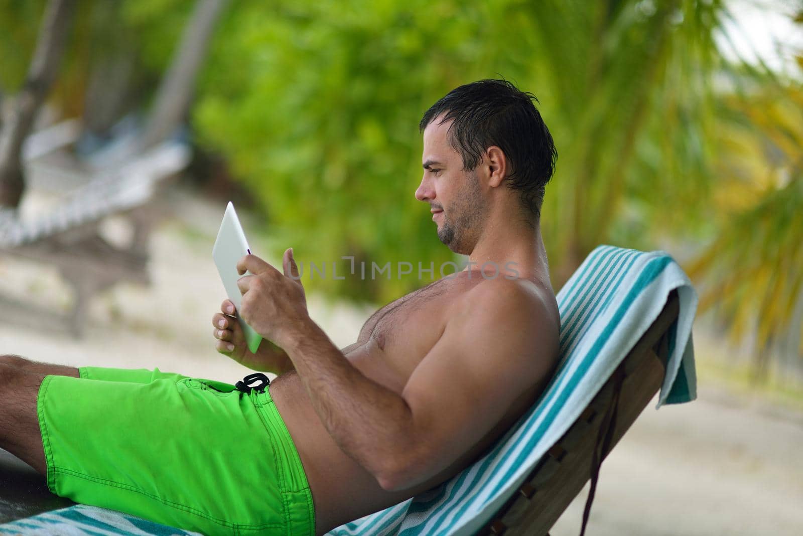 man ralaxing and use tablet at beach by dotshock