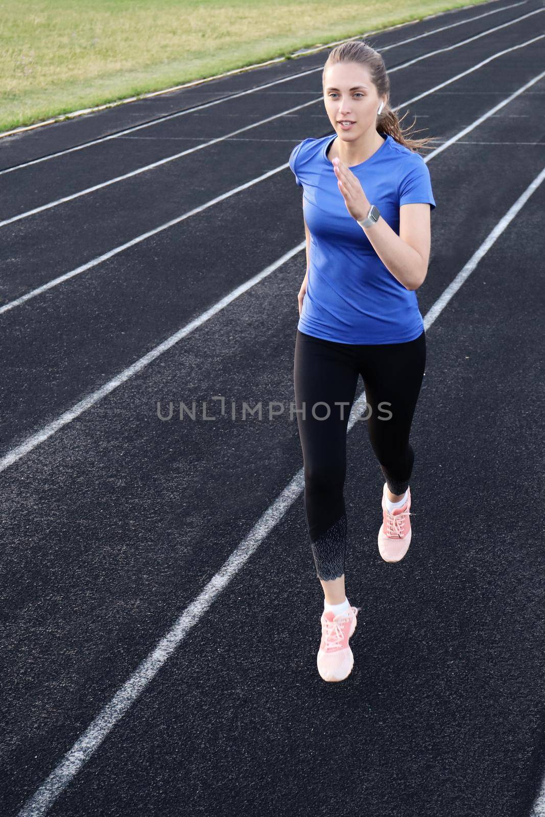 Runner athlete running on athletic track training her cardio in stadium. Jogging at fast pace for competition by tsyhun