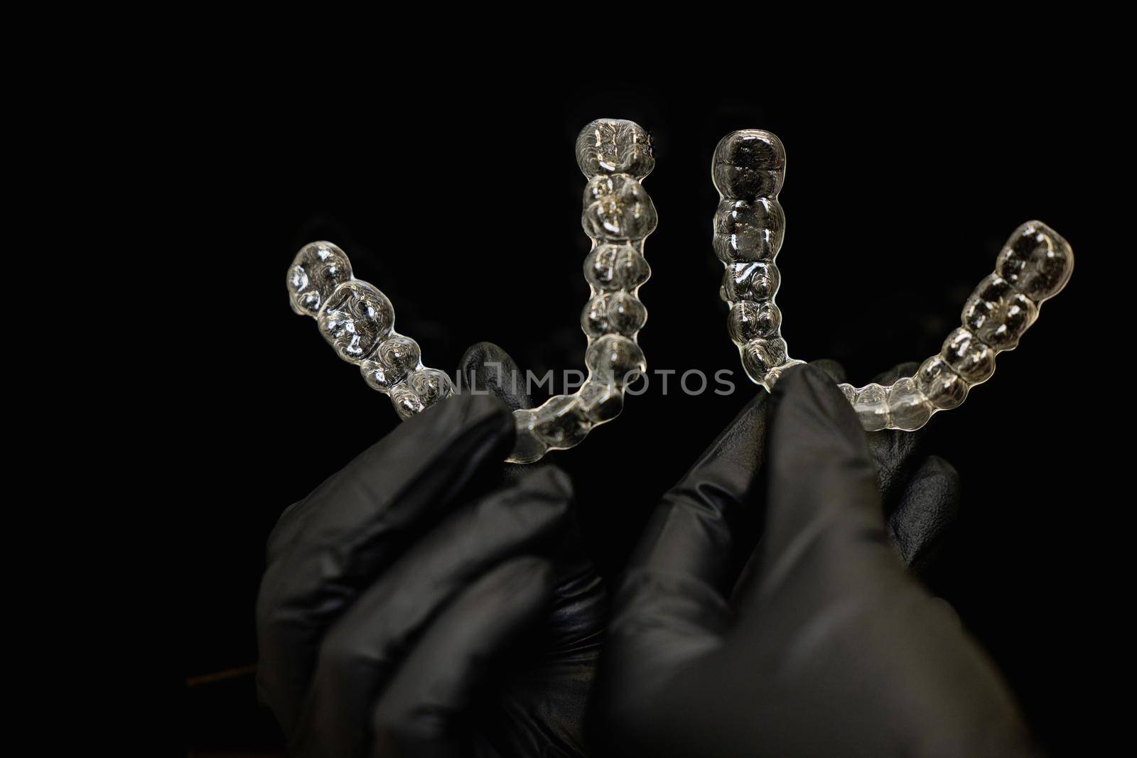 Close-up shot of doctors hands in black gloves holding silicone mouth guard. Teeth care. High quality photo