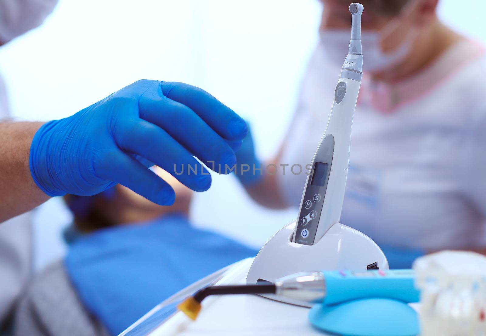 Detail of hand holding dental tools in dental clinic. Dentist Concept by lenets