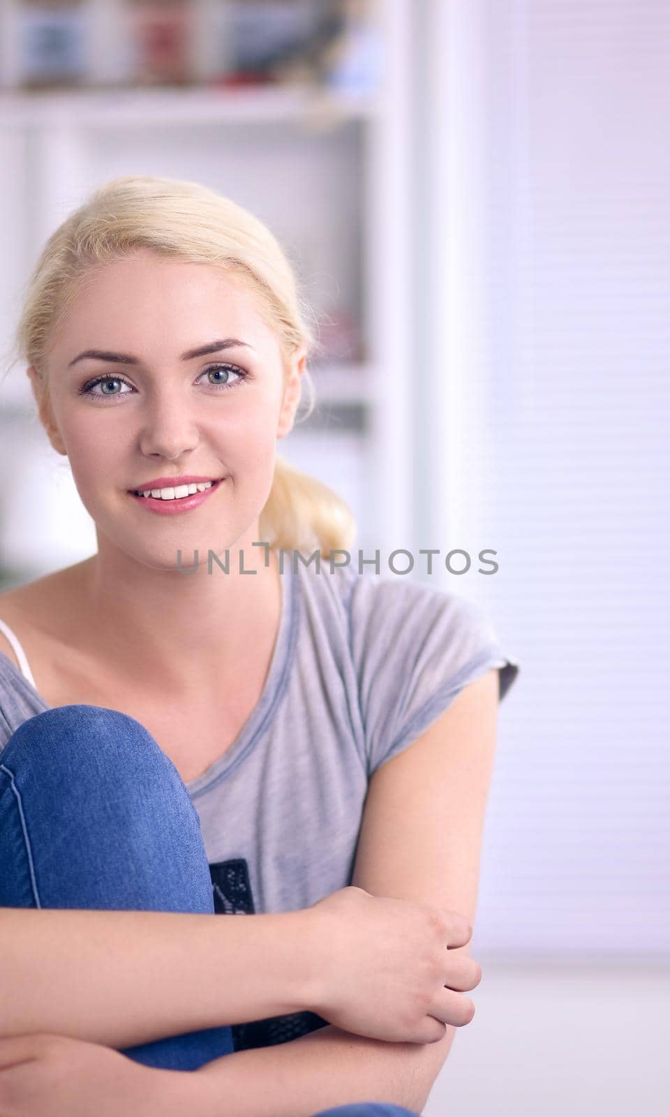 Young beautiful woman sitting on couch at her room .