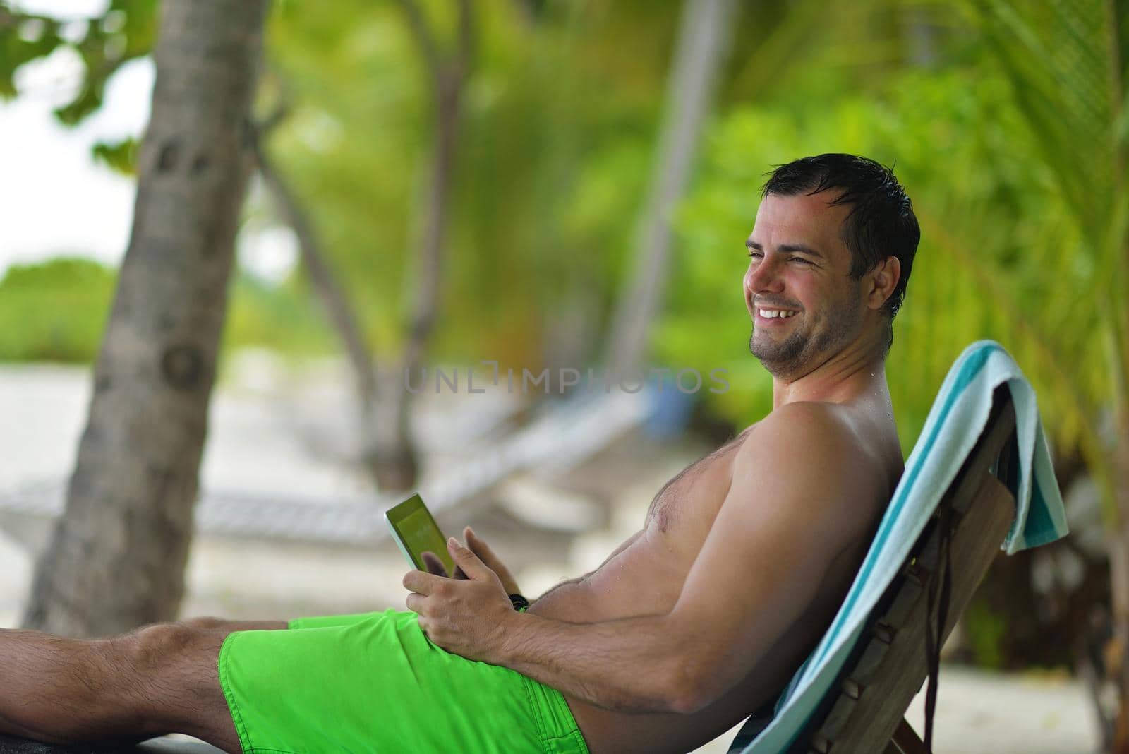 man ralaxing and use tablet at beach by dotshock