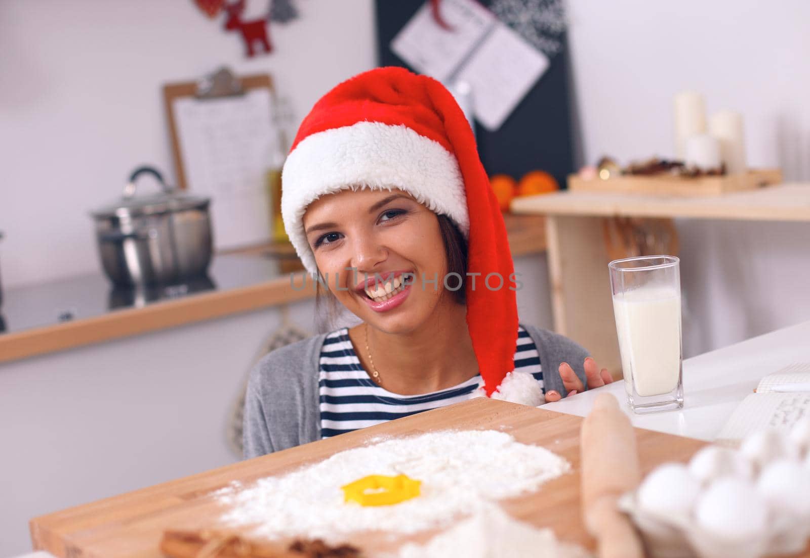 Happy young woman smiling happy having fun with Christmas preparations wearing Santa hat by lenets
