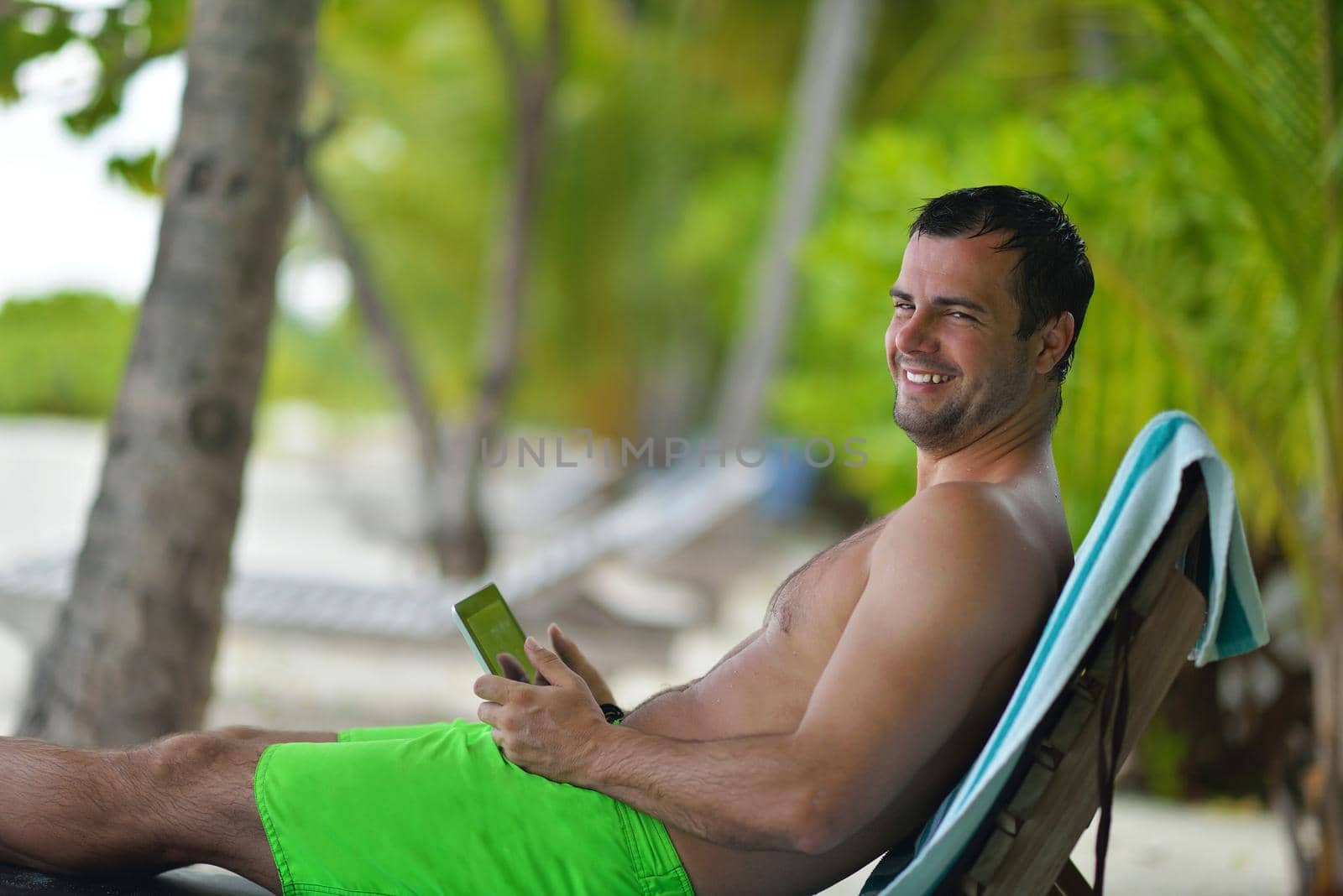 man ralaxing and use tablet at beach by dotshock