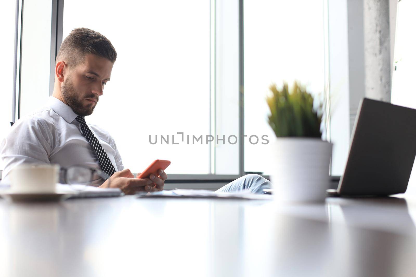 Portrait of happy businessman sitting at office desk by tsyhun