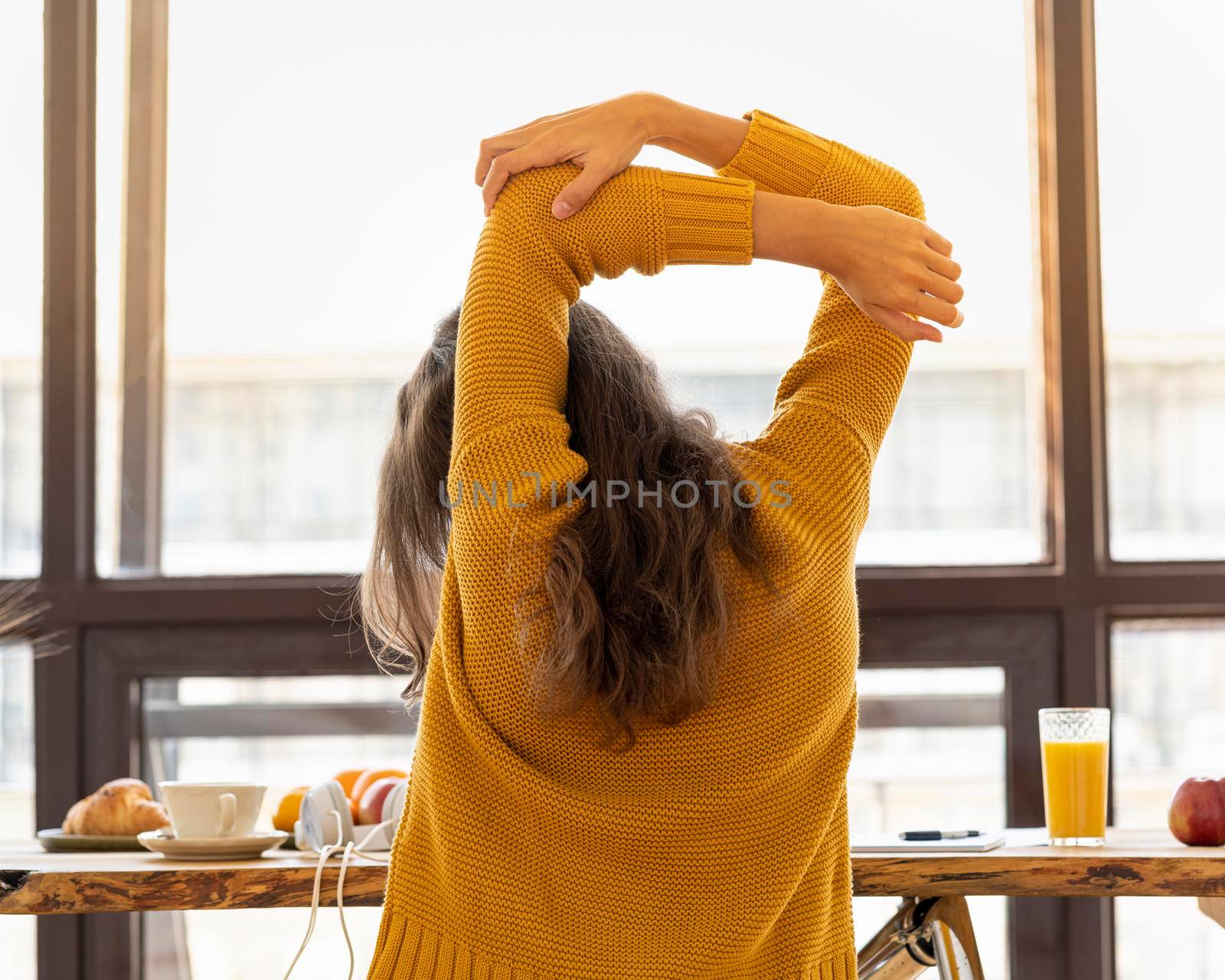 Back view of faceless young woman with stiff muscles, tense and joints ache. Stretching of limbs, warm-up, exercise at workplace, pull-up