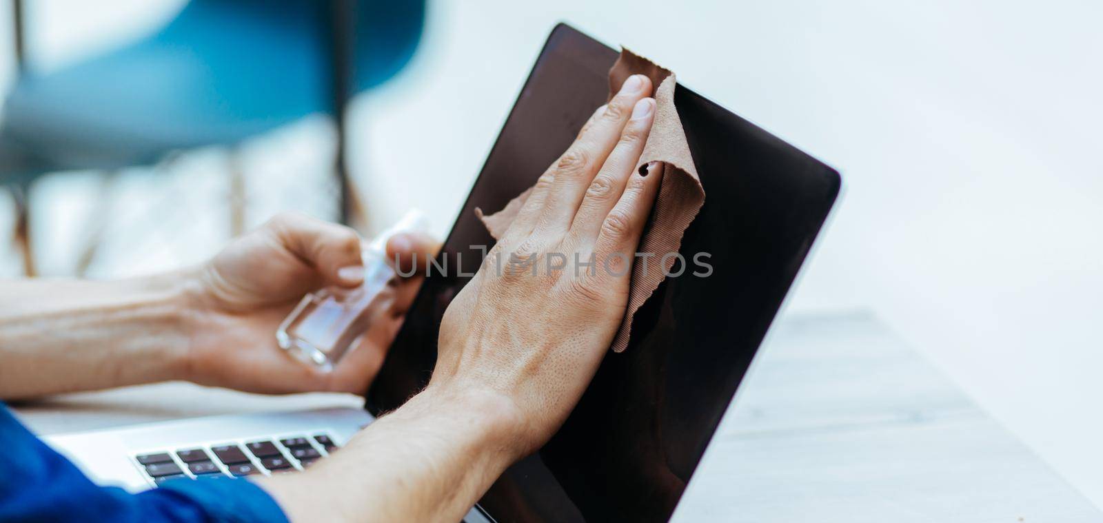 close up. a young man in a protective mask wiping the screen of his laptop by SmartPhotoLab
