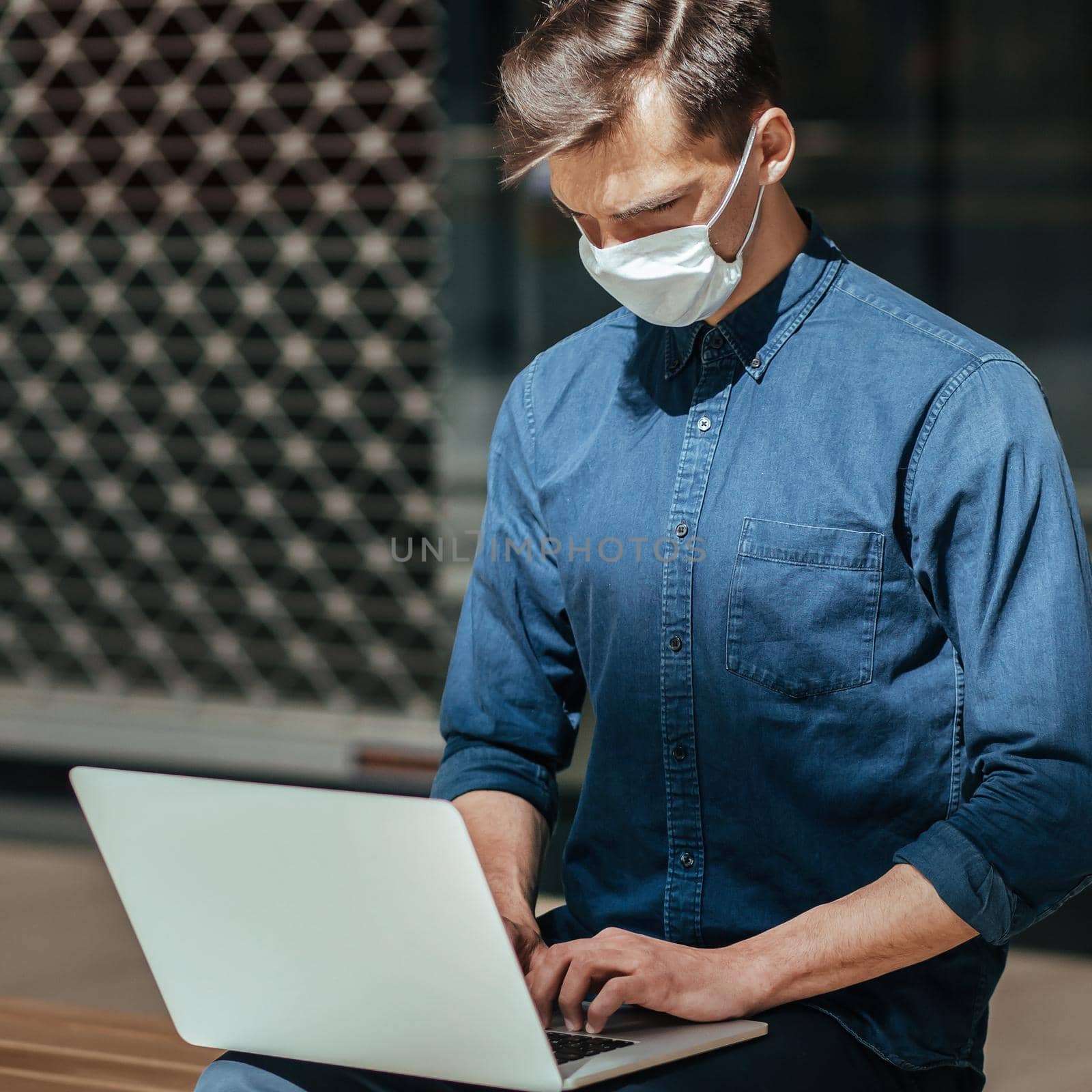 close up. city guy in a protective mask is working on a laptop. concept of health protection.