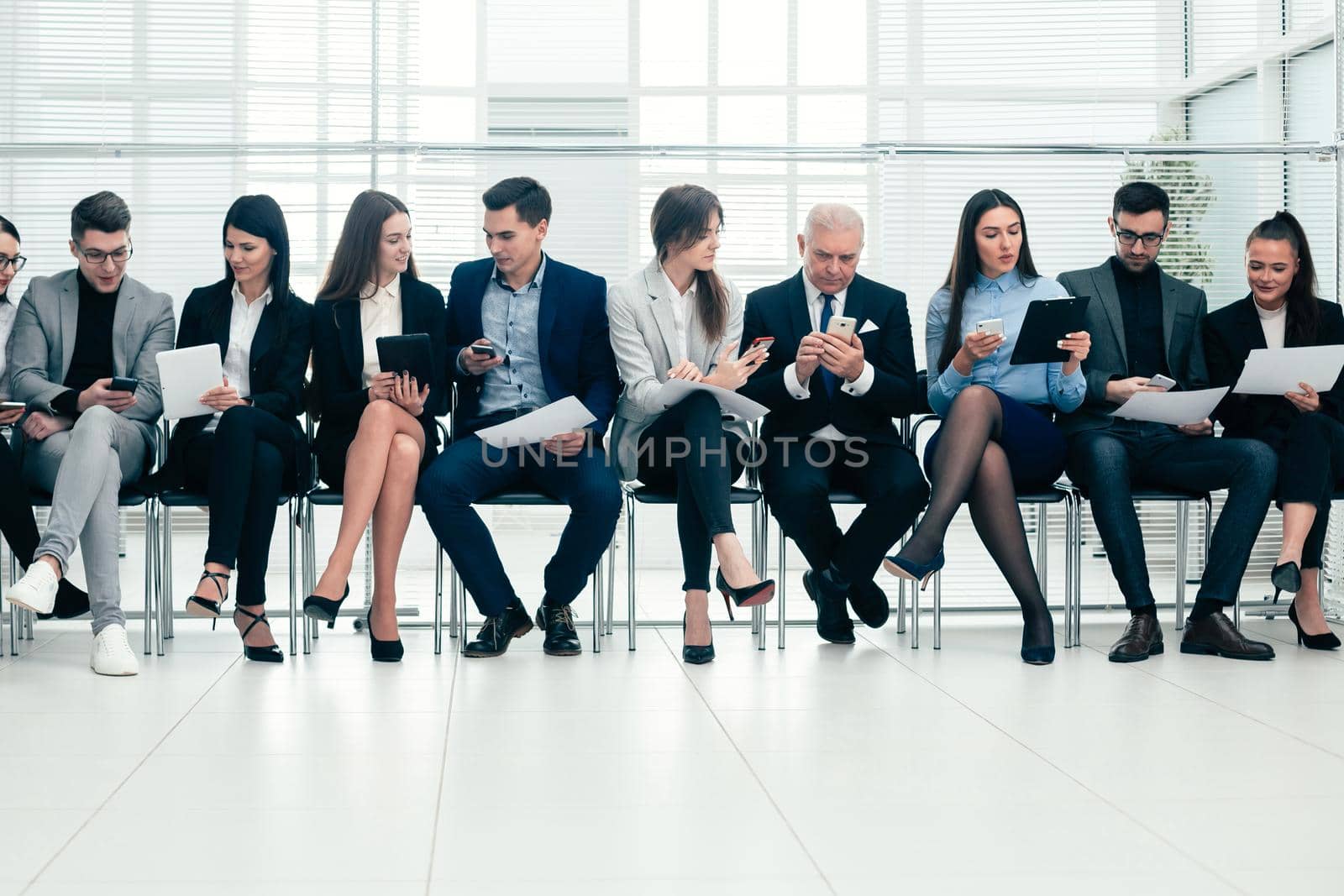 group of employees using their devices in the conference room. by SmartPhotoLab