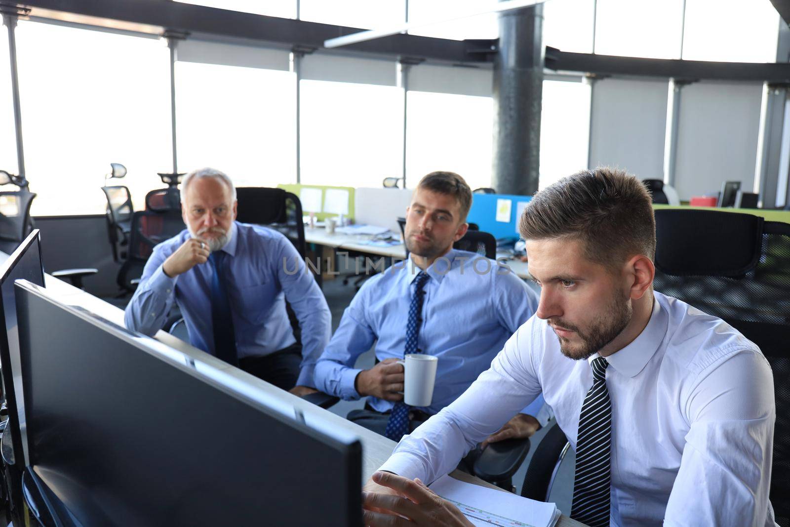 Group of young business men in formalwear working using computers while sitting in the office