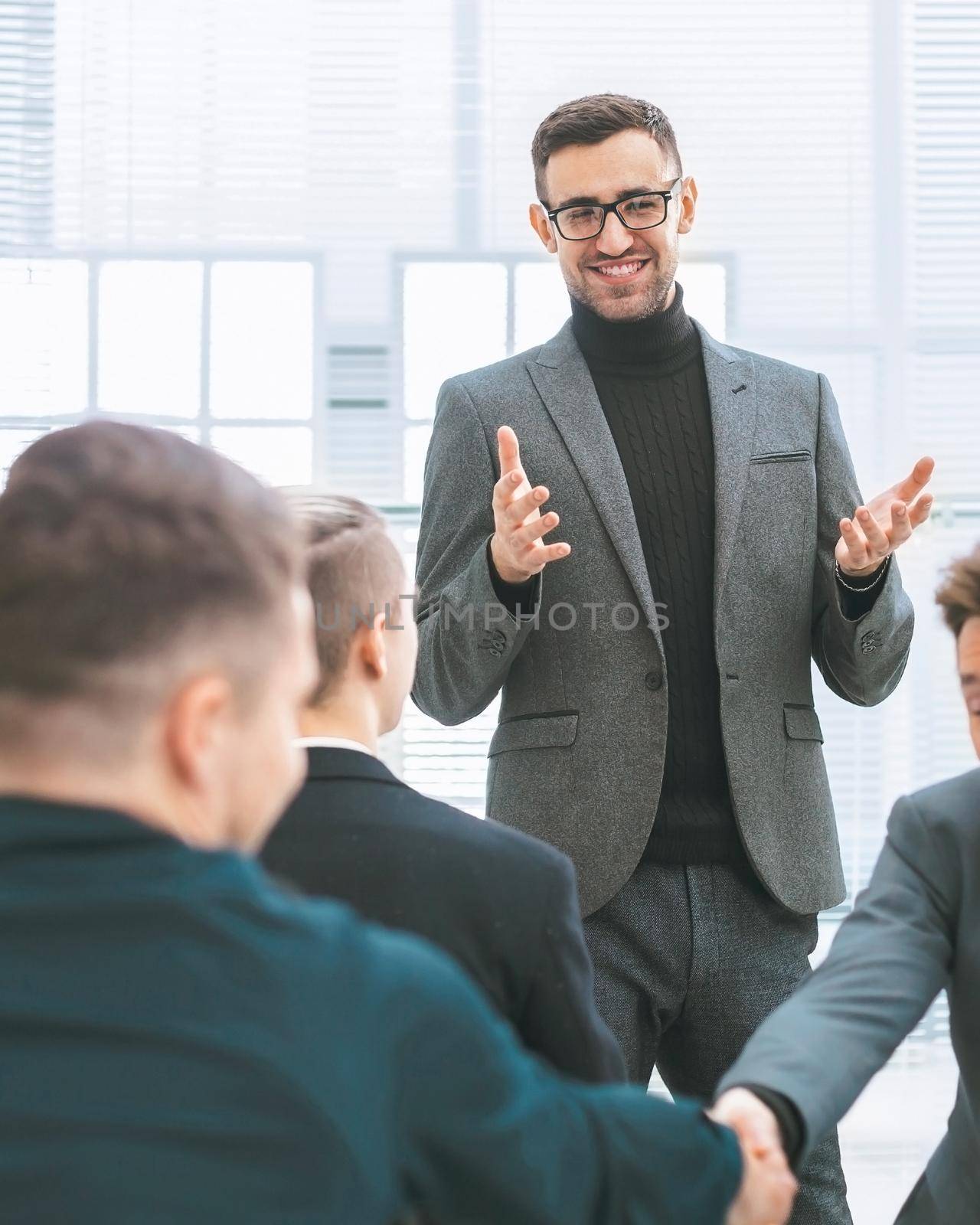 smiling employees shaking hands during a working meeting . business concept