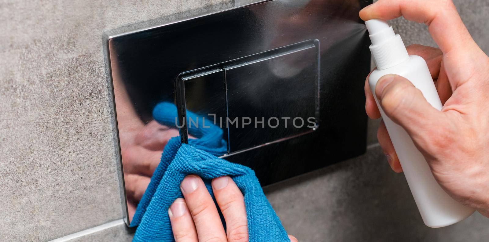 close up. man spraying an antibacterial spray on a wall switch. by SmartPhotoLab