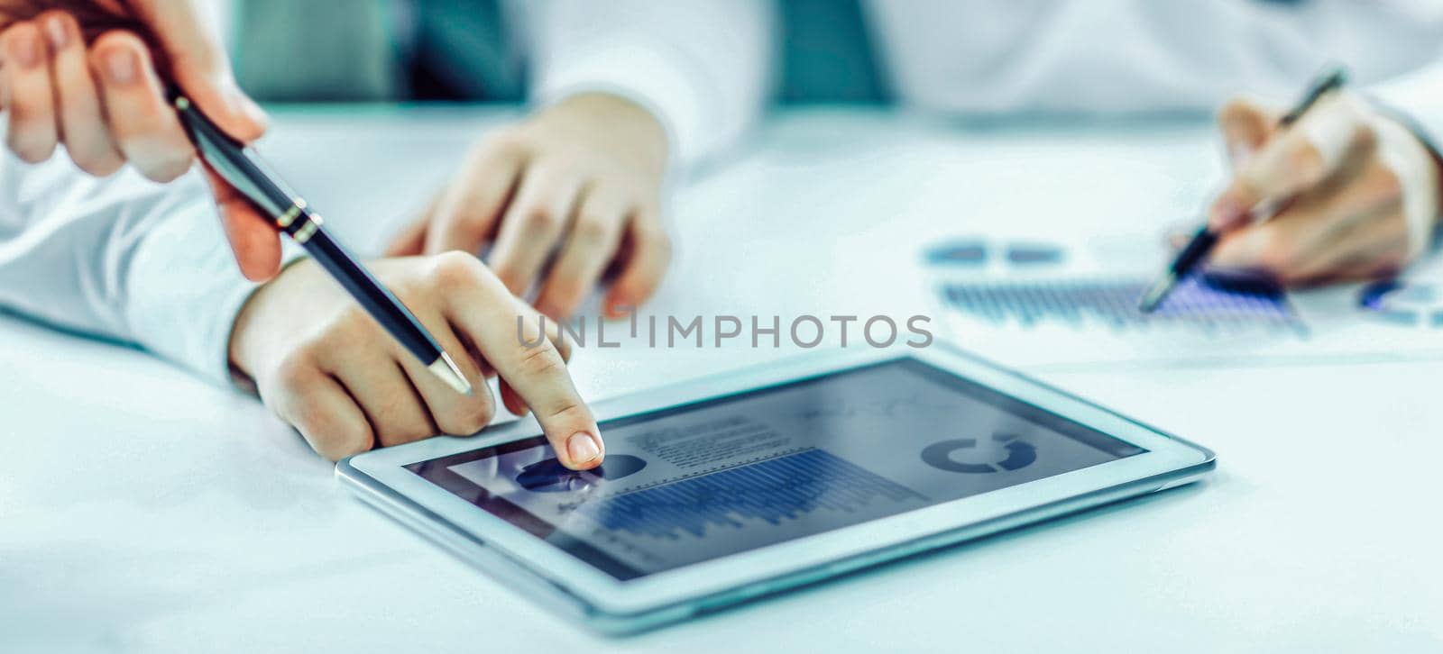 closeup of businessman using digital tablet, working with the financial schedule at the Desk .the photo has a empty space for your text