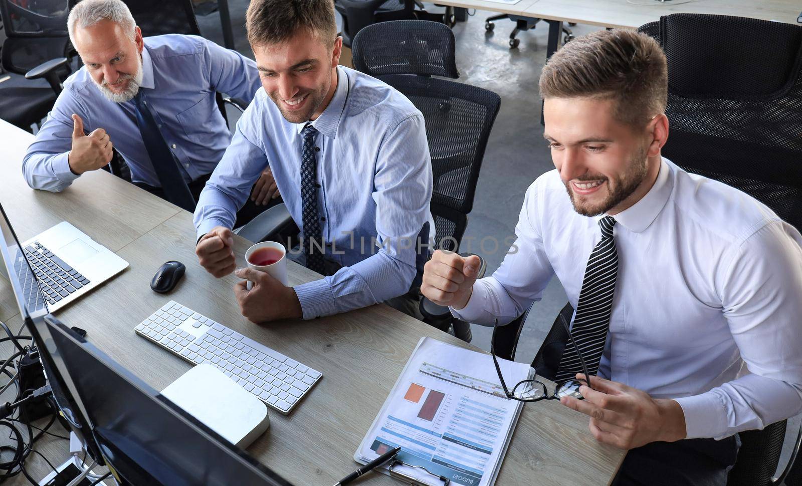 Group of modern business men in formalwear smiling and gesturing while working in the office
