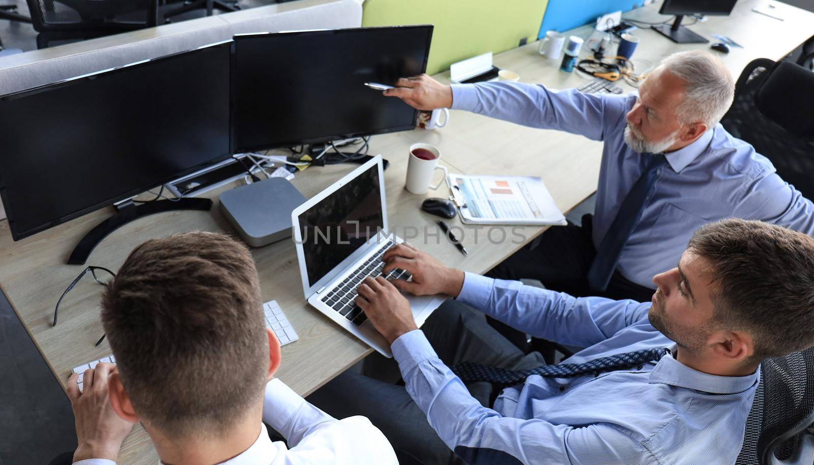 Group of young business men in formalwear working using computers while sitting in the office. by tsyhun