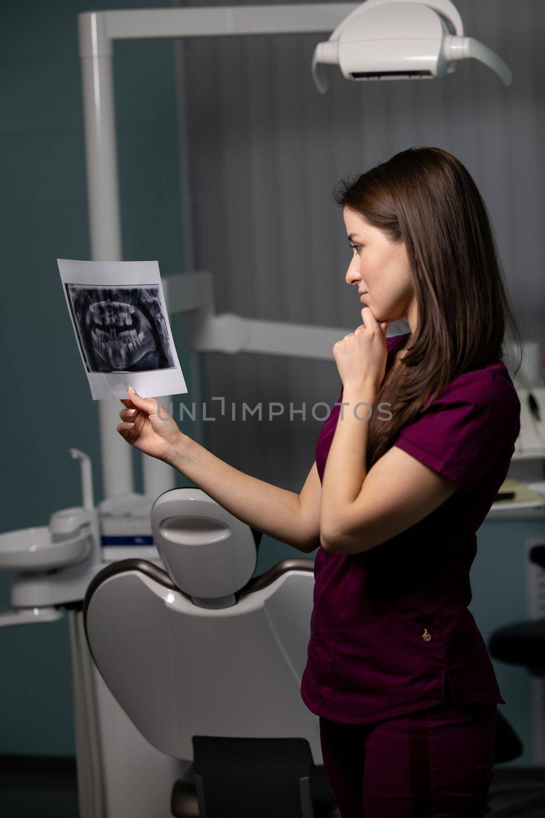 Beautiful woman doctor with dental scans in hands in a dental clinic by yulikov