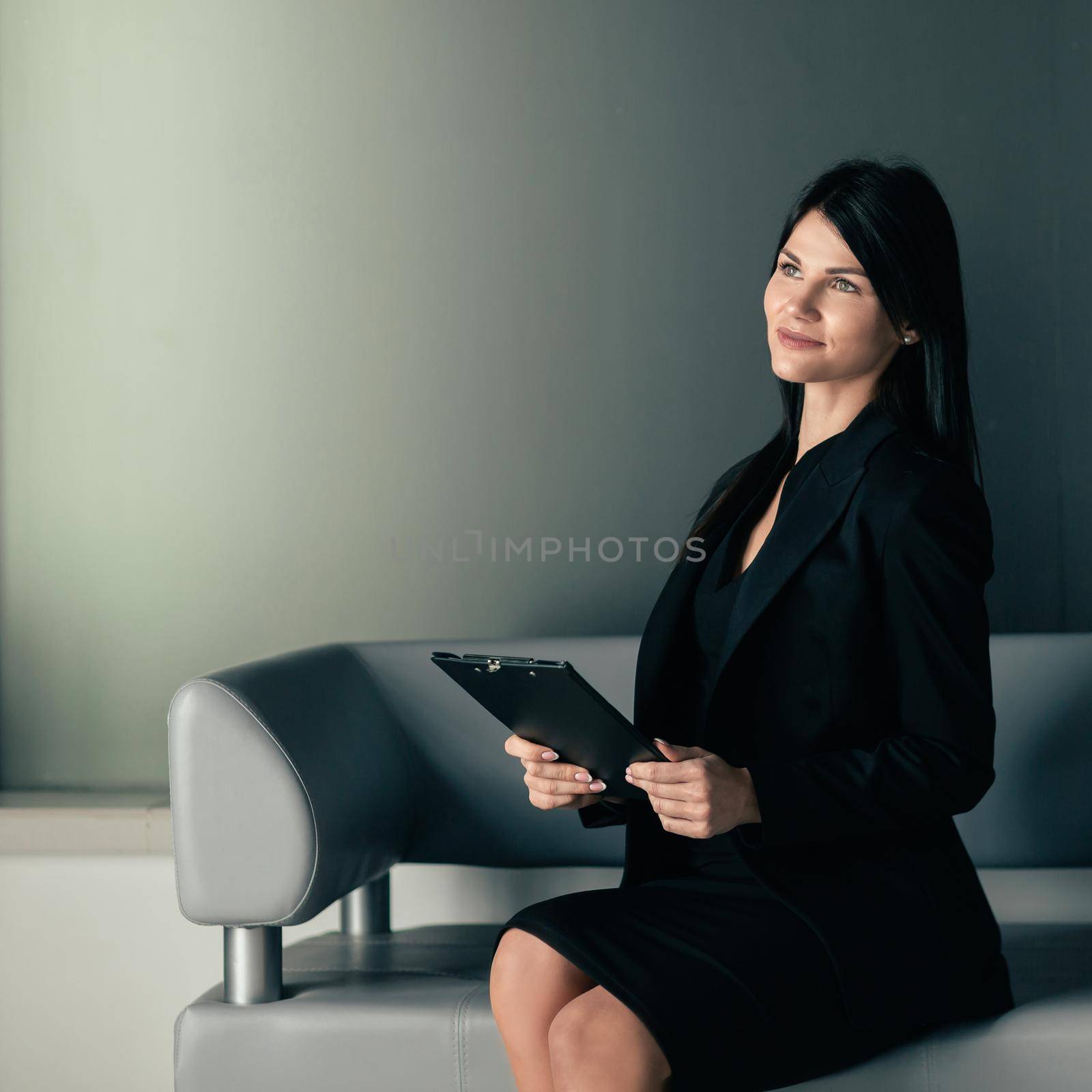 smiling business woman sitting in office lobby. photo with a copy of the space