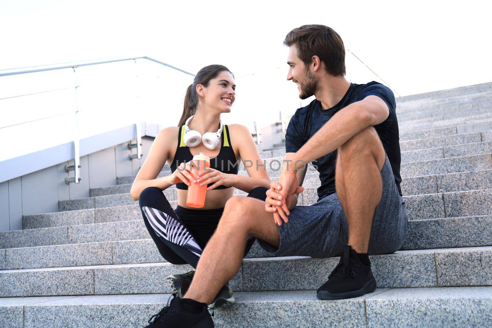 Young couple in sportswear sitting on the stairs after exercising outdoors. by tsyhun