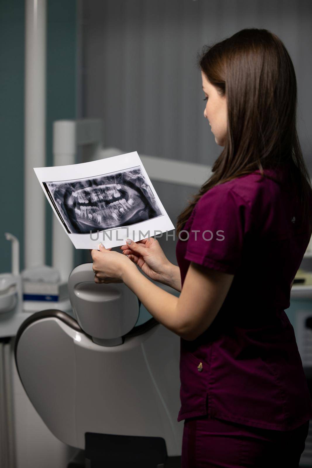 Beautiful woman doctor with dental scans in hands in a dental clinic by yulikov