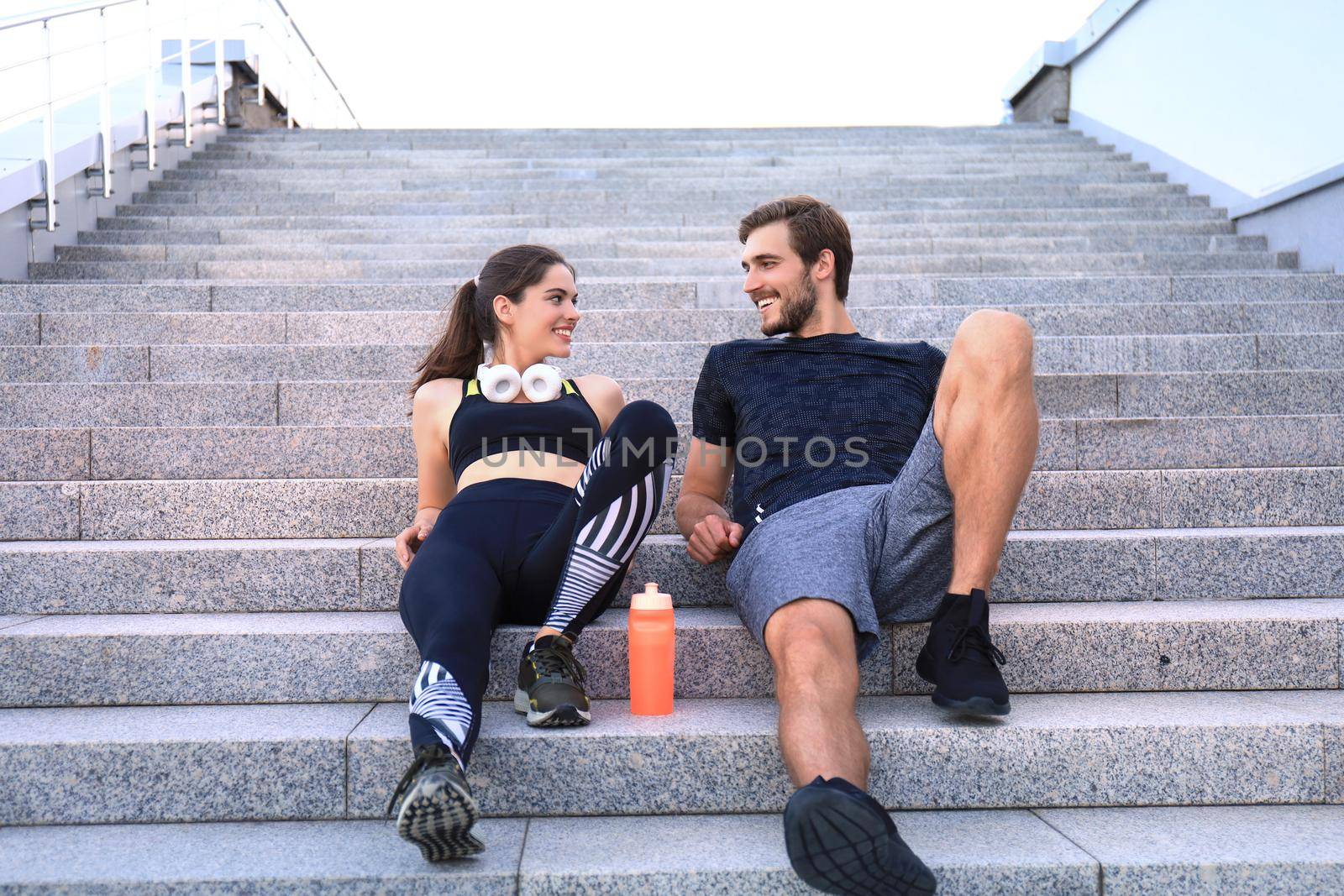 Young couple in sportswear sitting on the stairs after exercising outdoors. by tsyhun