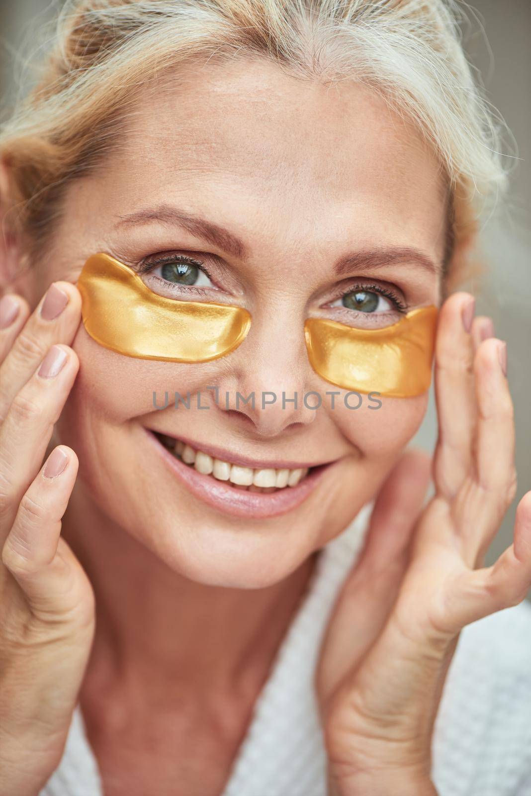 Under eye patches on smiling caucasian woman face by friendsstock