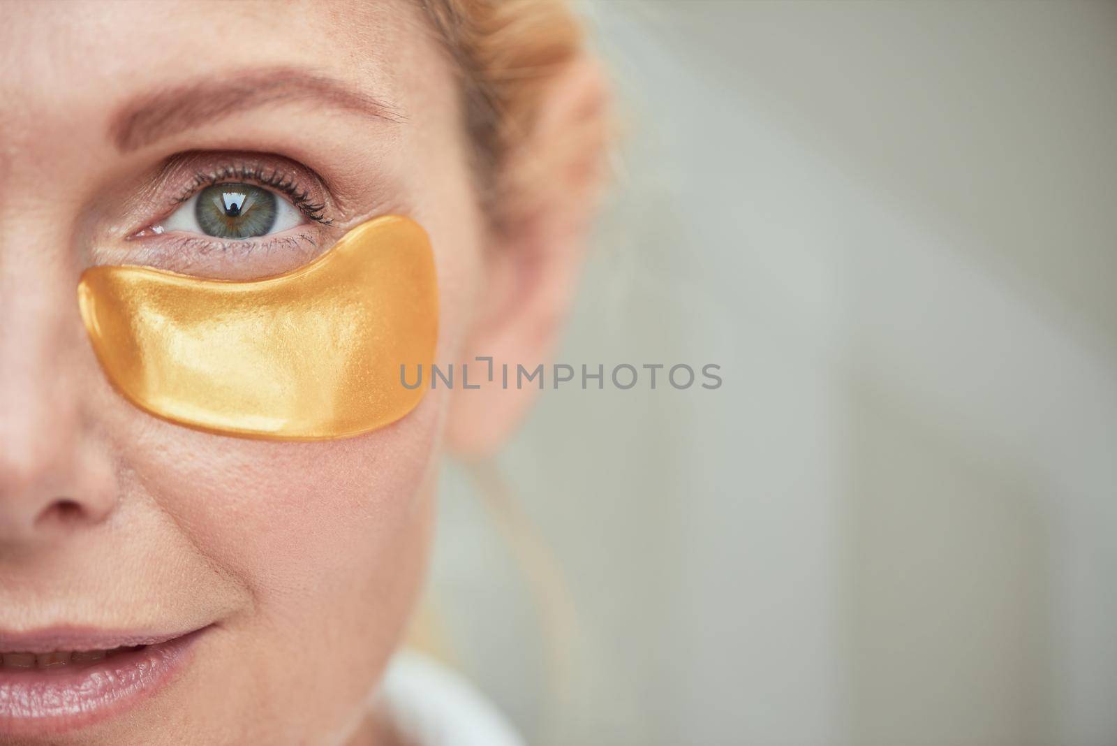 Under eye patch on smiling middle aged caucasian woman face, selective focus. Beauty, skincare and cosmetology concept