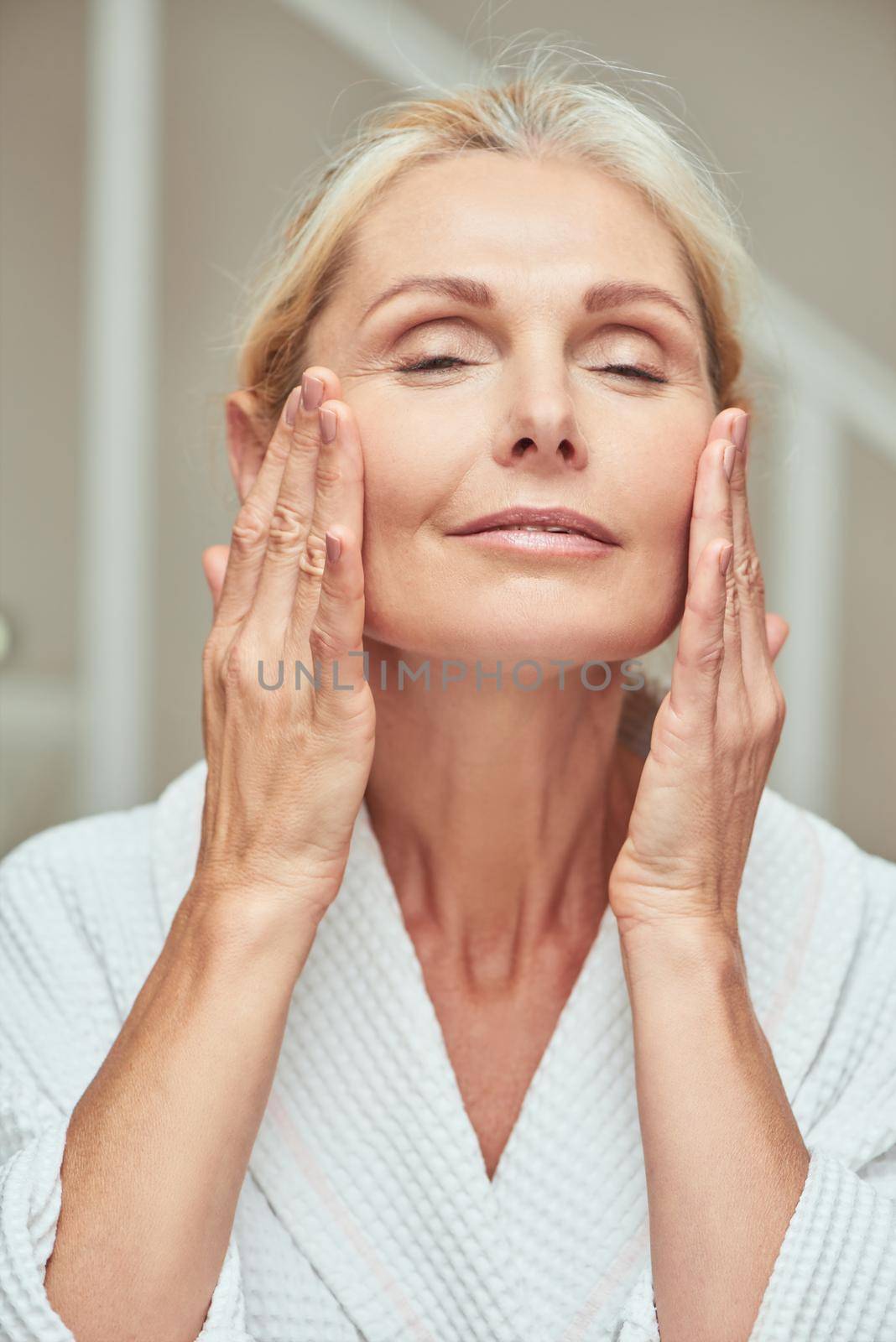 Happy middle aged caucasian woman making facial massage by friendsstock