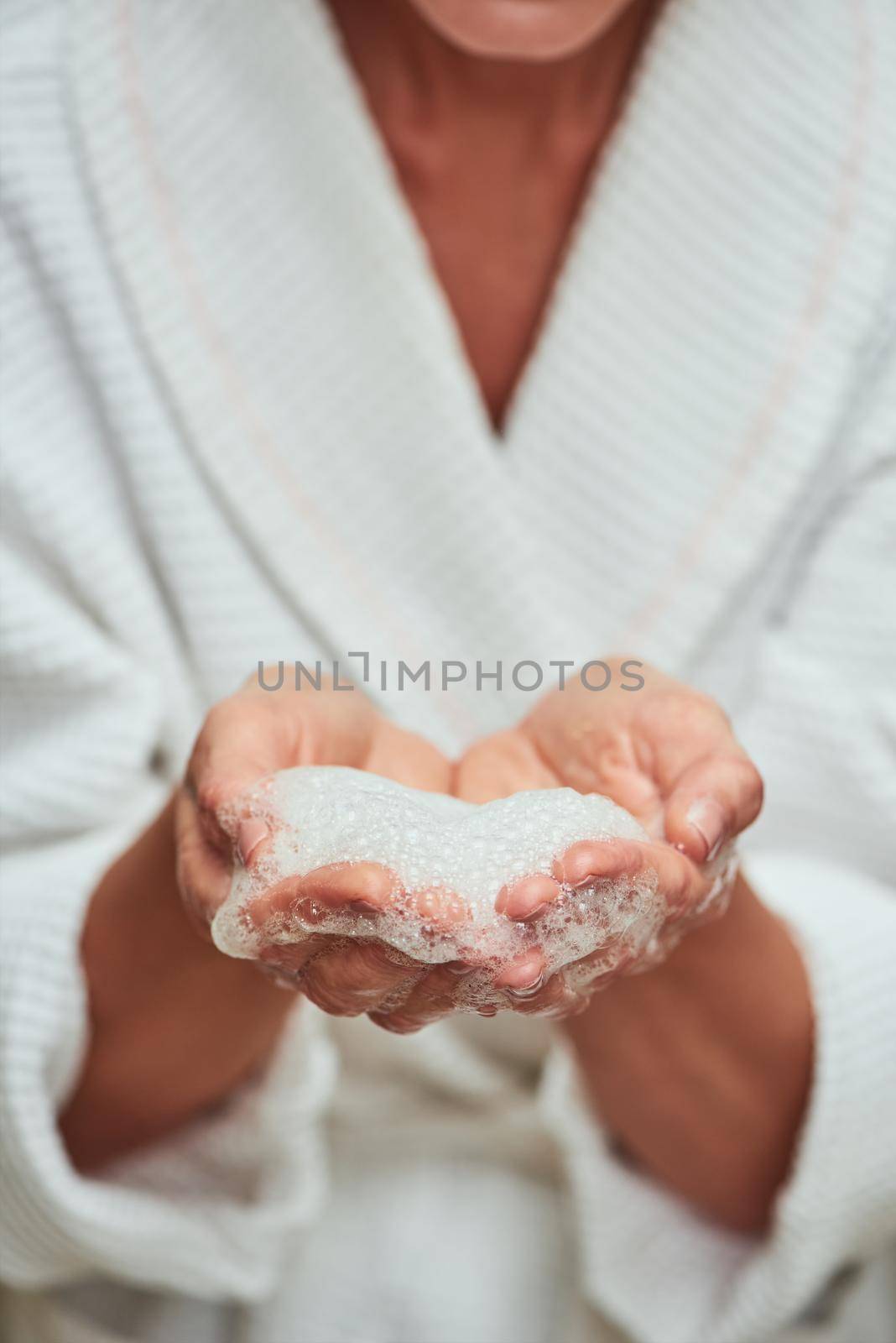Soap foam in female hands during spa procedure. Beauty, skincare and cosmetology concept