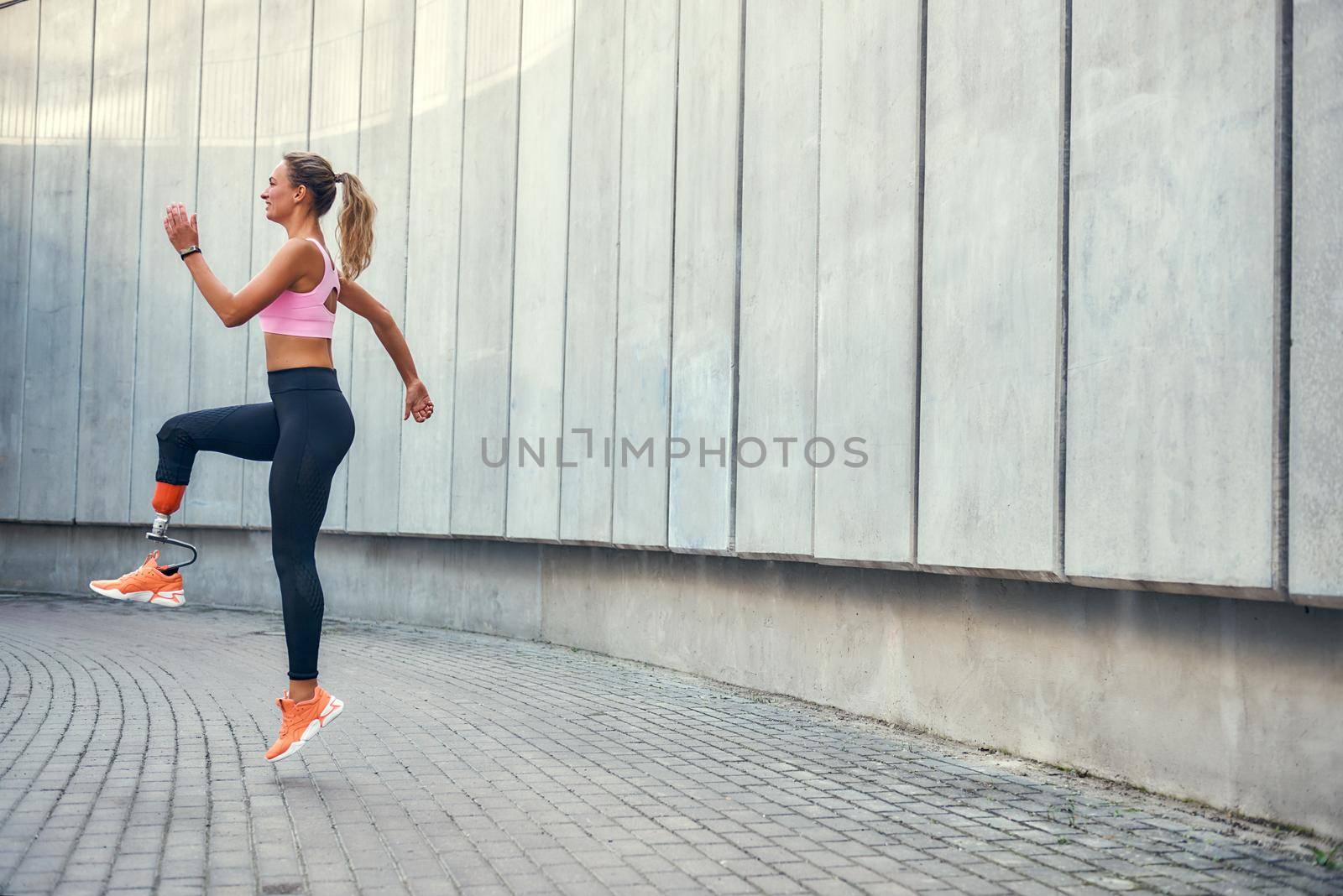 No limits Active disabled woman with leg prosthesis in sports clothing jumping while her morning workout outdoors. Disabled sport concept. Motivation. Healthy lifestyle