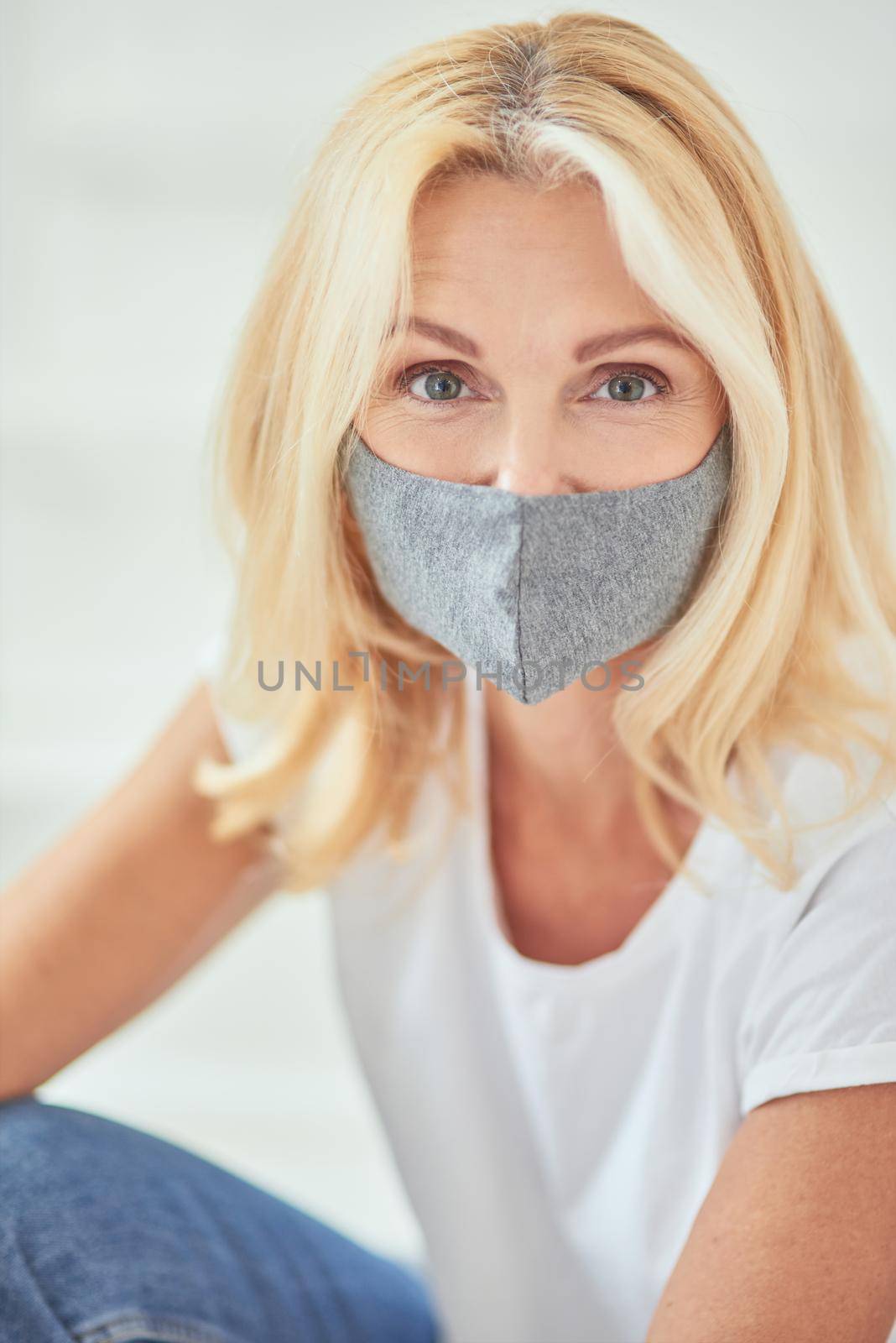 Portrait of middle aged caucasian woman in face mask looking at camera on white background. Isolation at home concept
