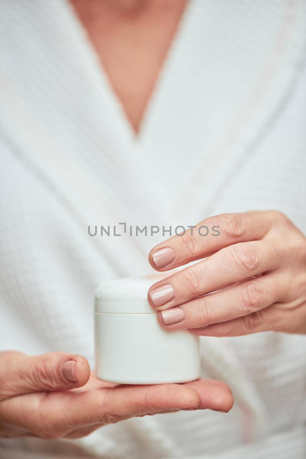 Cream bottle in manicured woman hands by friendsstock