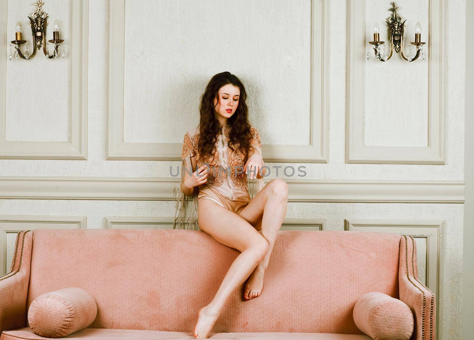 young pretty brunette girl in fashion dress on sofa posing in luxury rich home interior, lifestyle modern people concept close up