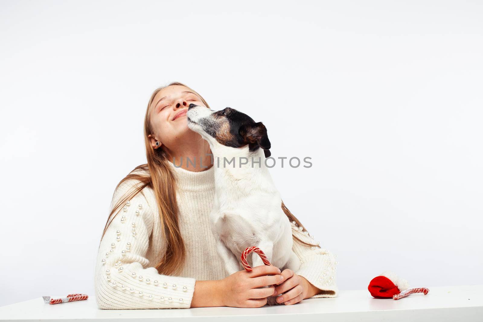 pretty young blond girl with her little cute dog wearing Santas red hat at Christmas holiday isolated on white background, lifestyle people concept close up