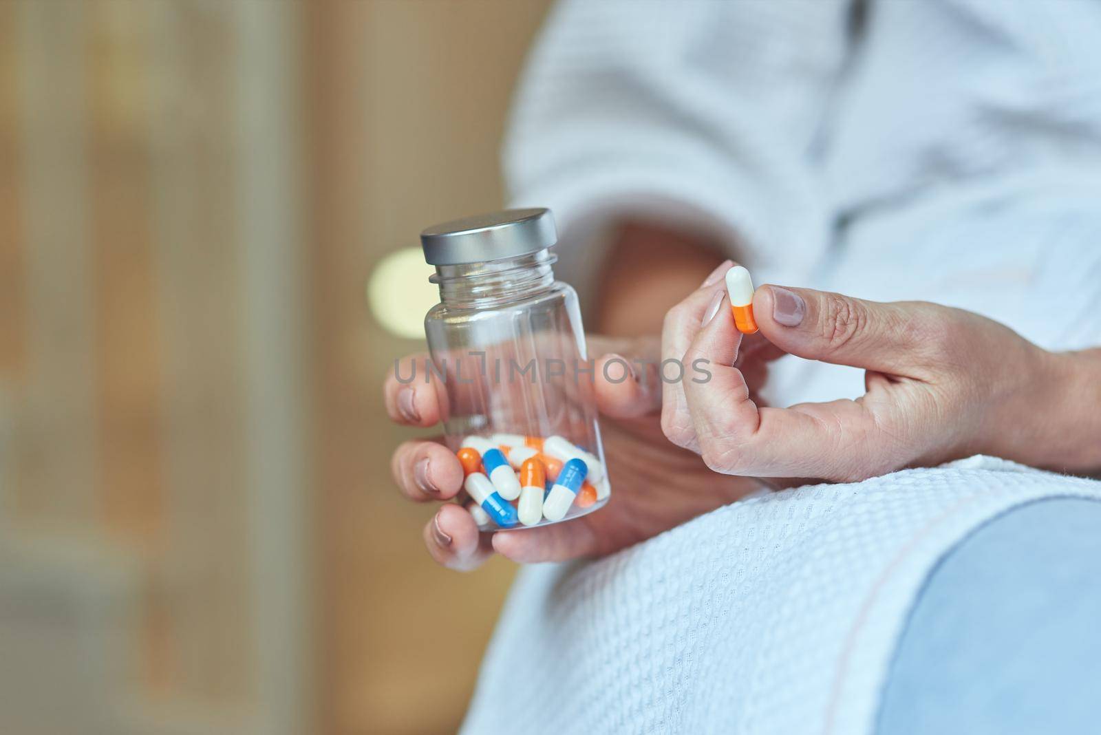 Capsule and bottle of tablets in female hands by friendsstock