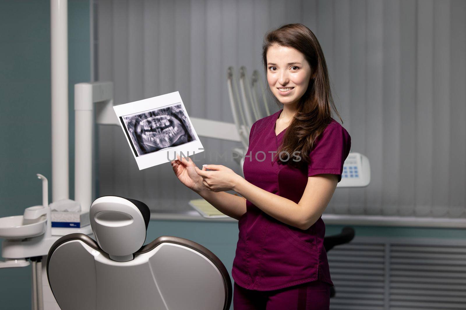 Beautiful woman doctor with dental scans in hands in a dental clinic by yulikov