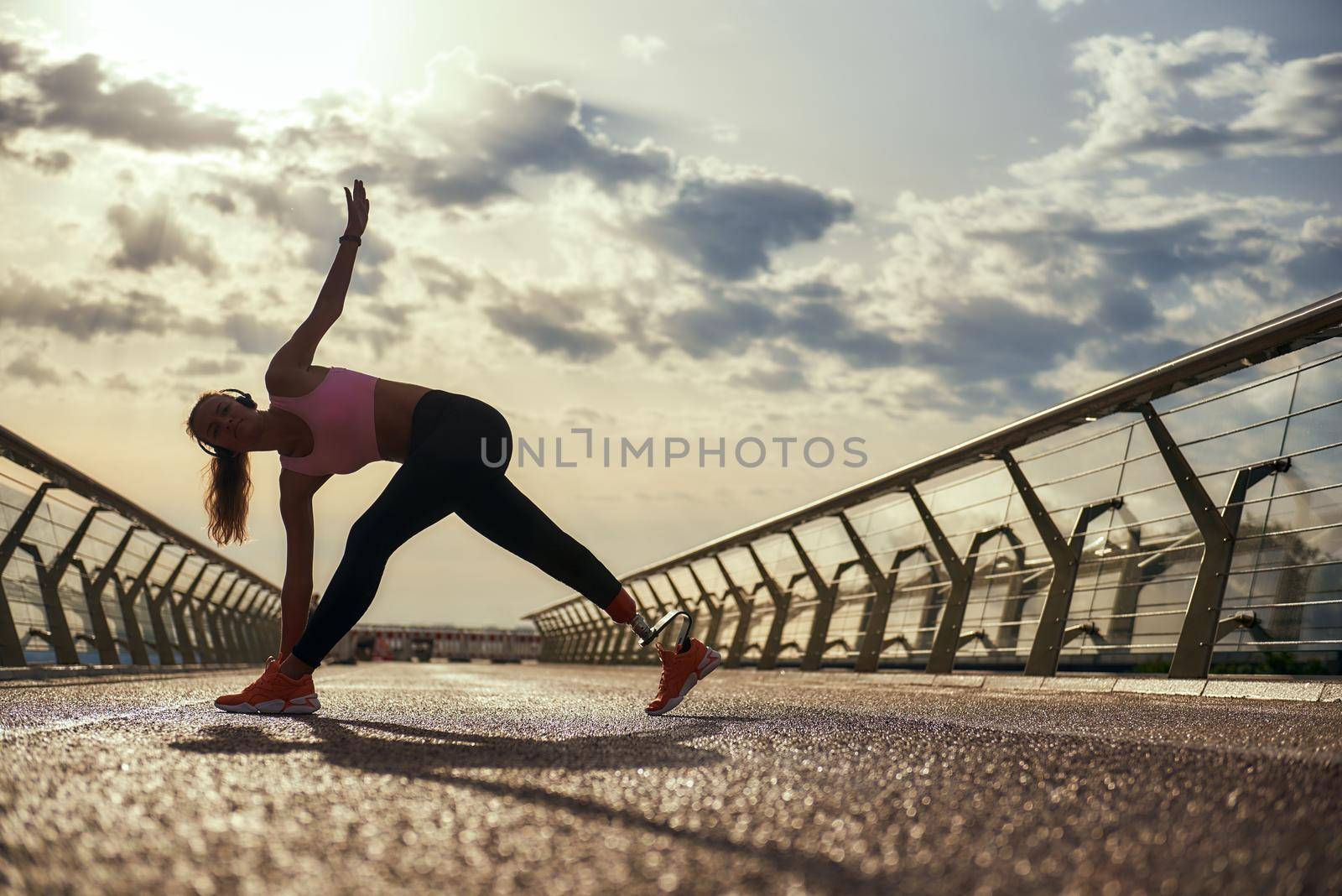 Morning workout. Full-length of young disabled woman with leg prosthesis in sportswear doing yoga exercises while standing on the bridge. Disabled sport concept. Motivation. Healthy lifestyle