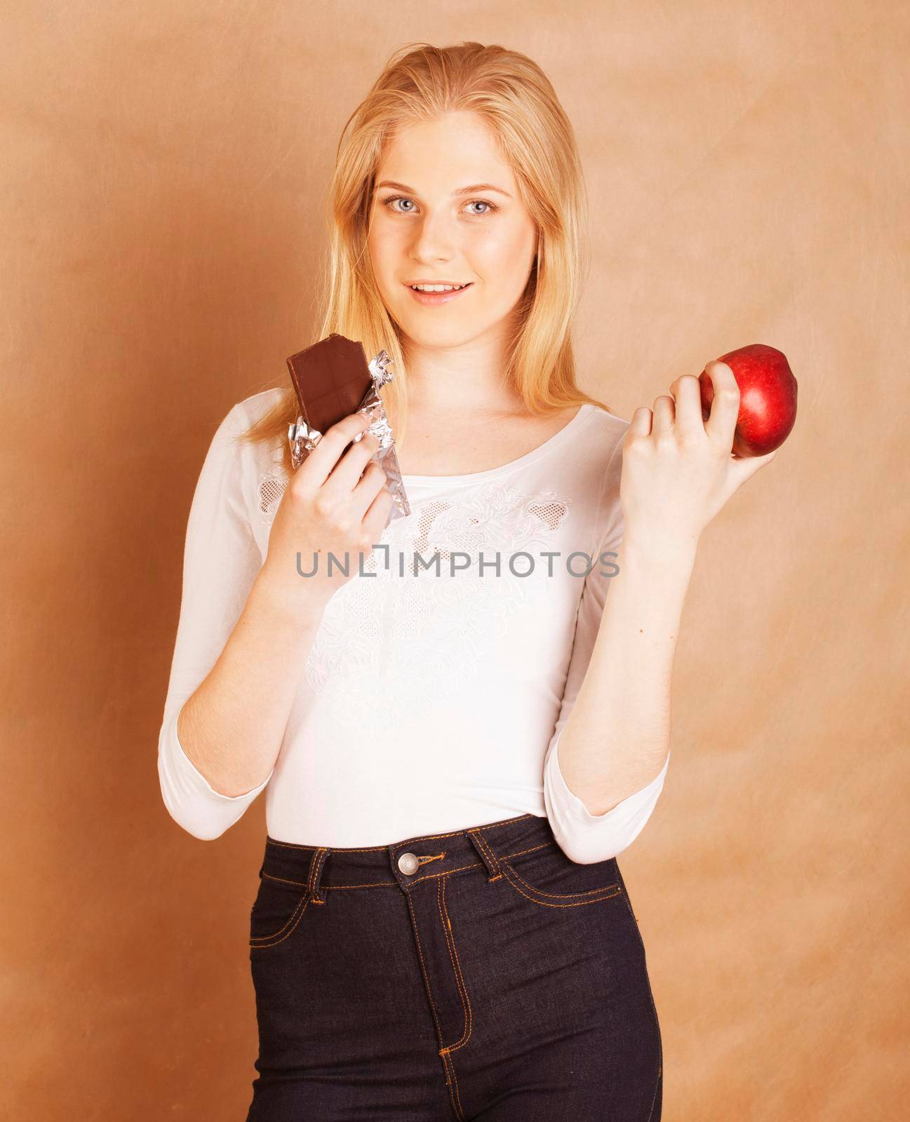young beauty blond teenage girl eating chocolate smiling, choice between sweet and apple by JordanJ
