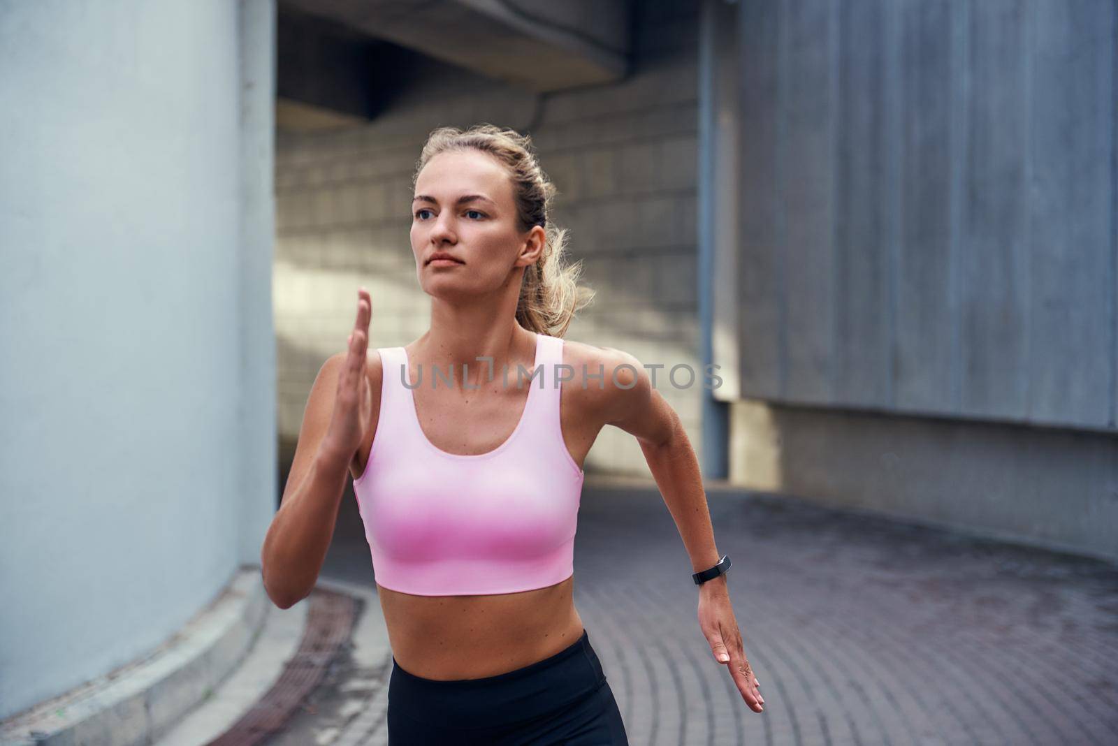 Morning cardio. Young woman in comfortable sports clothing is running outdoors along the street by friendsstock