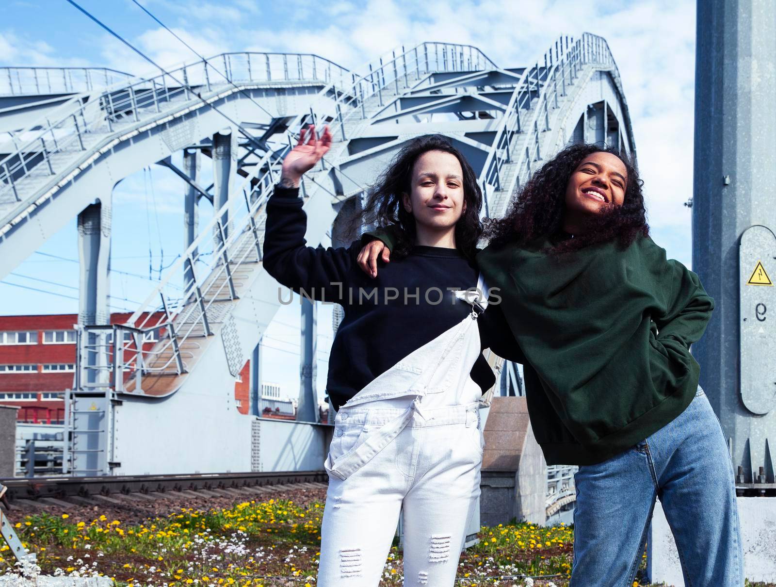 young cute teenage girls together in industrial zone happy smiling having fun, big city lifestyle fashion people close up