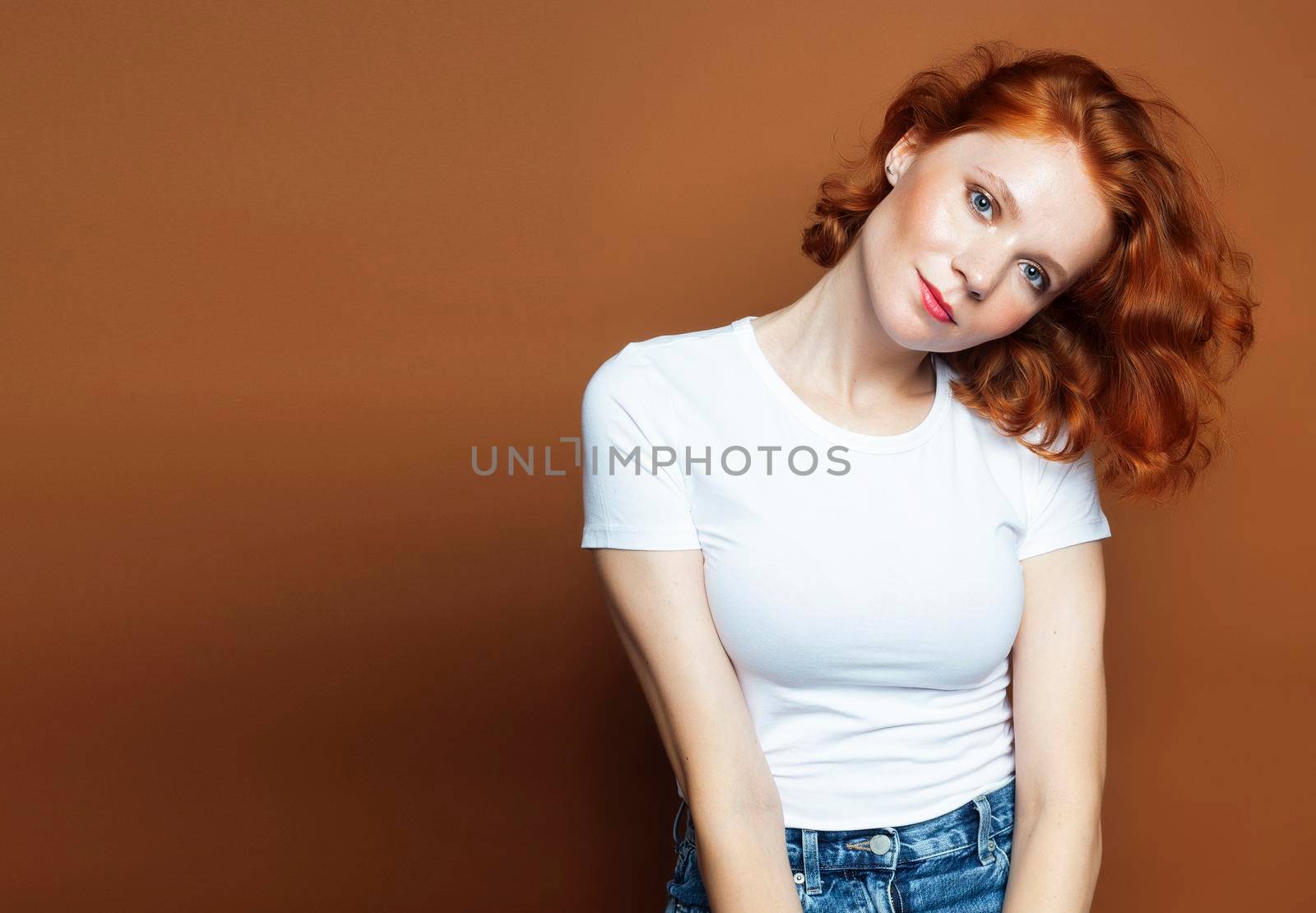 young pretty redhead girl posing cheerful on warm brown background, lifestyle people concept close up
