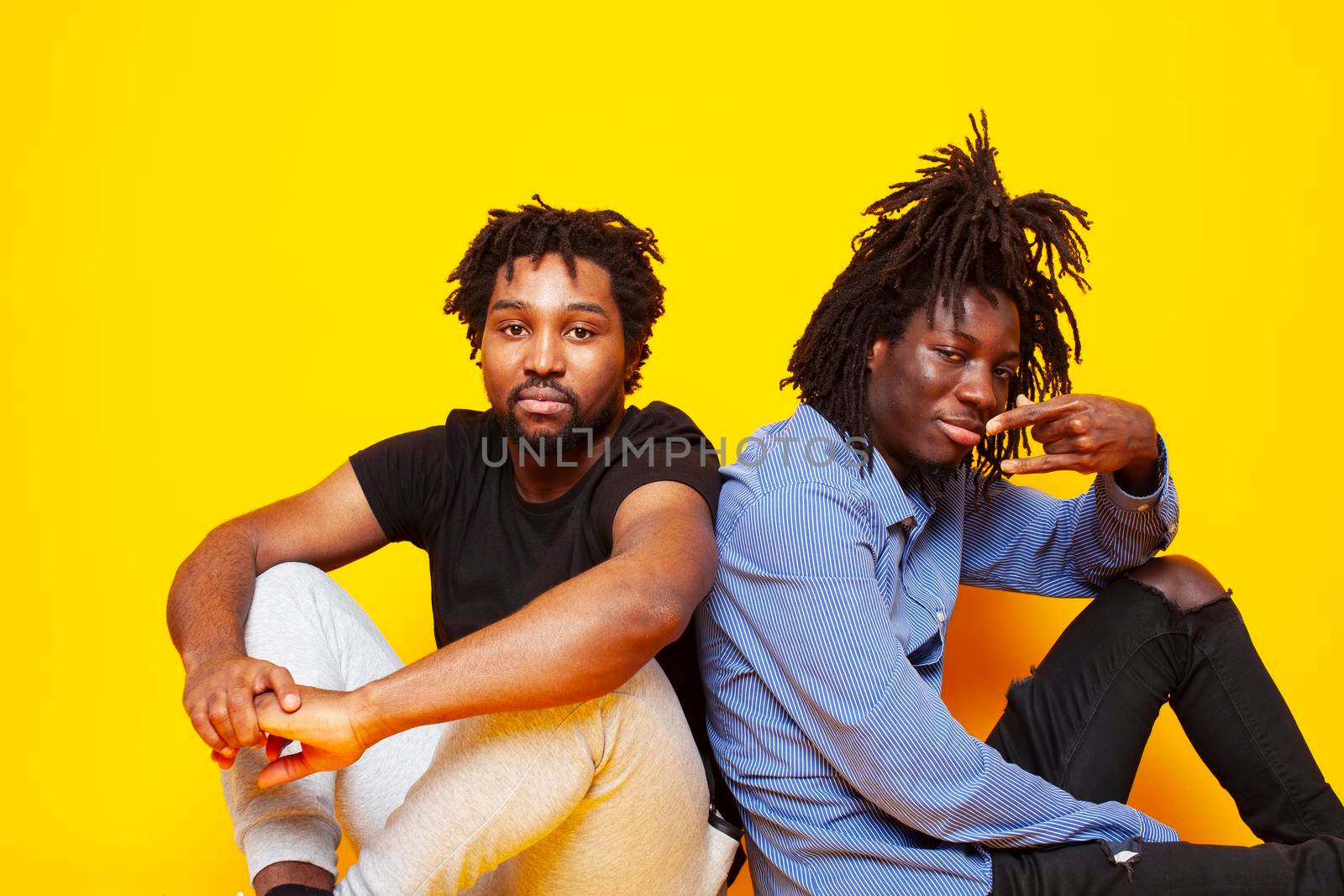 two african american guys posing cheerful together on yellow background, lifestyle people concept close up