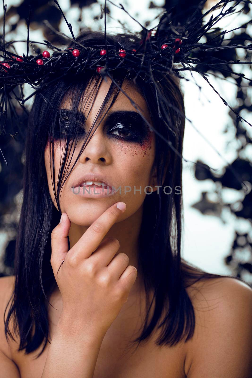 pretty brunette woman with make up like demon at halloween, closeup scary background