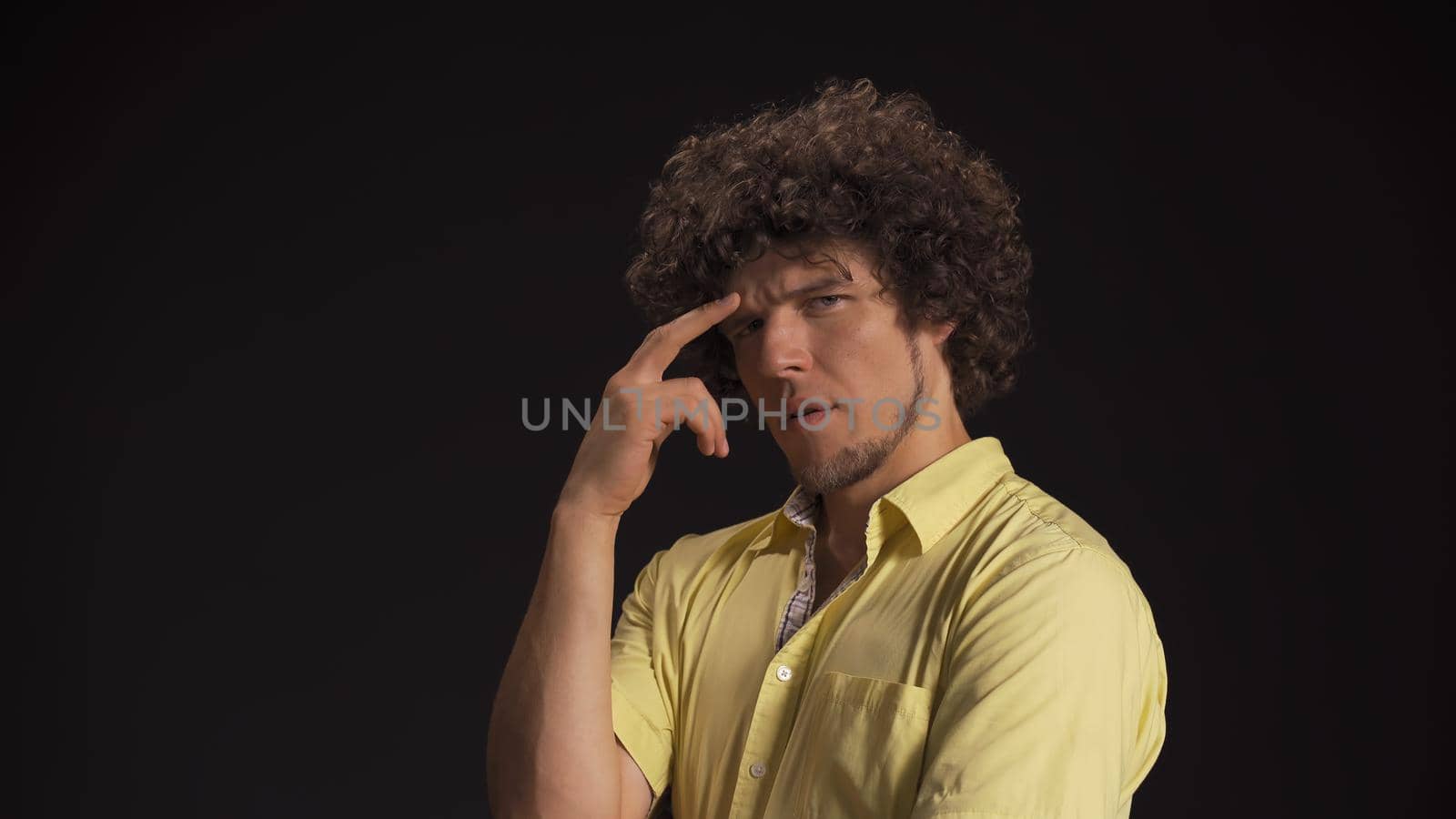 Serious thoughtful man generates idea while touching his forehead with fingers. Isolated on black background. High quality photo.