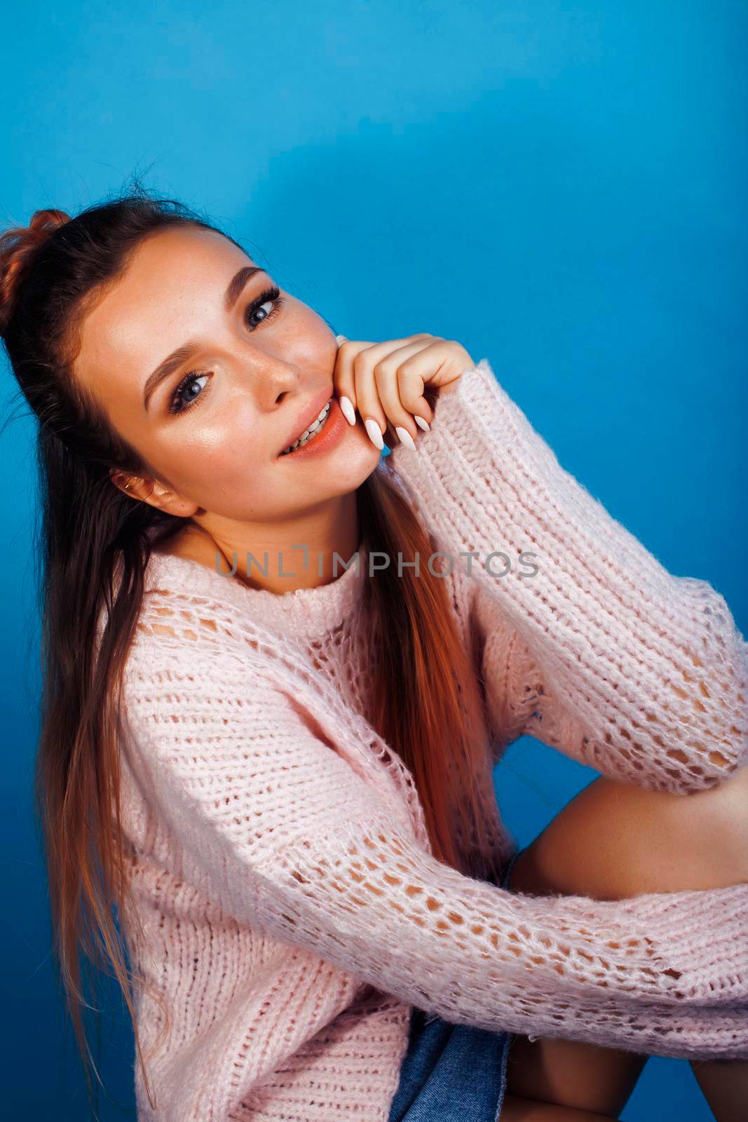 young pretty modern hipster girl posing emotional happy on blue background, lifestyle people concept close up