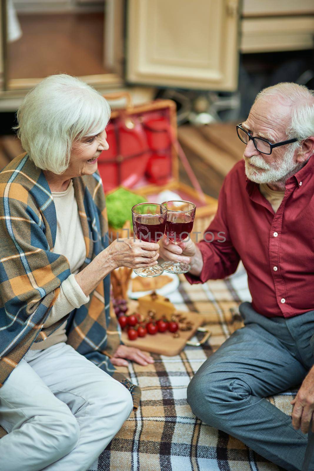 Smiling elderly couple enjoying the trip and celebrating with wine by friendsstock